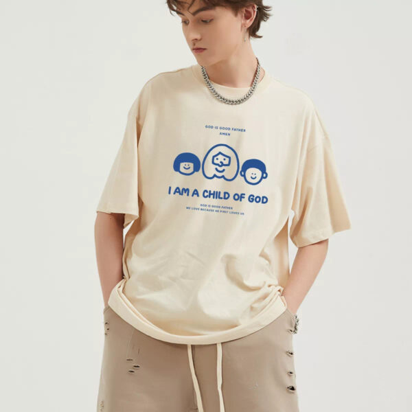 A man in a t-shirt that reads "I am a child of God," smiling and standing against a neutral background.